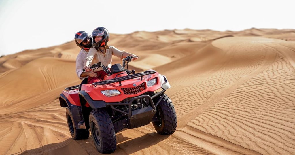 A high-performance Polaris RZR dune buggy kicking up a massive plume of sand while carving through the steep red dunes of the Lahbab Desert in Dubai.