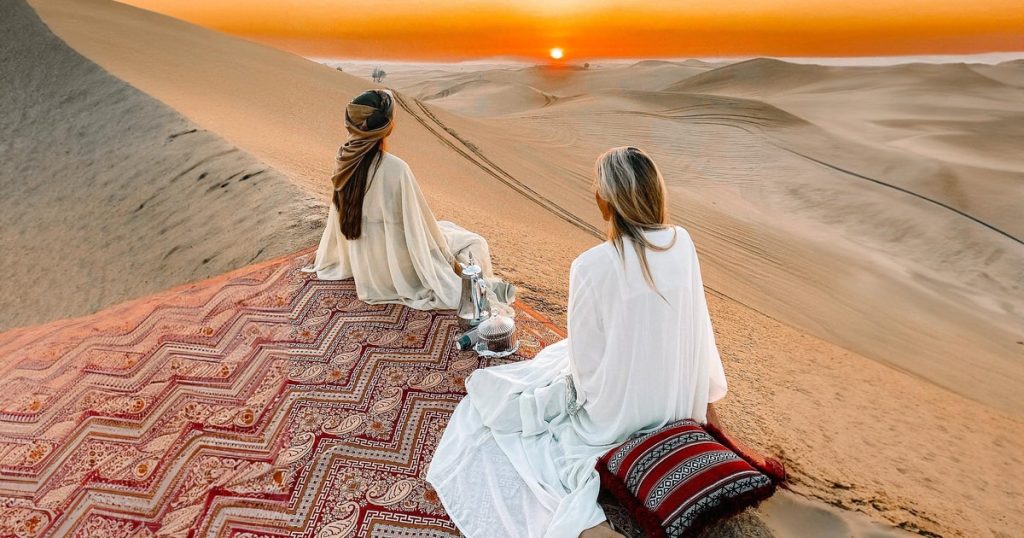 A group of quad bikers standing next to their vehicles in the middle of the desert, holding water bottles and looking out over the landscape.