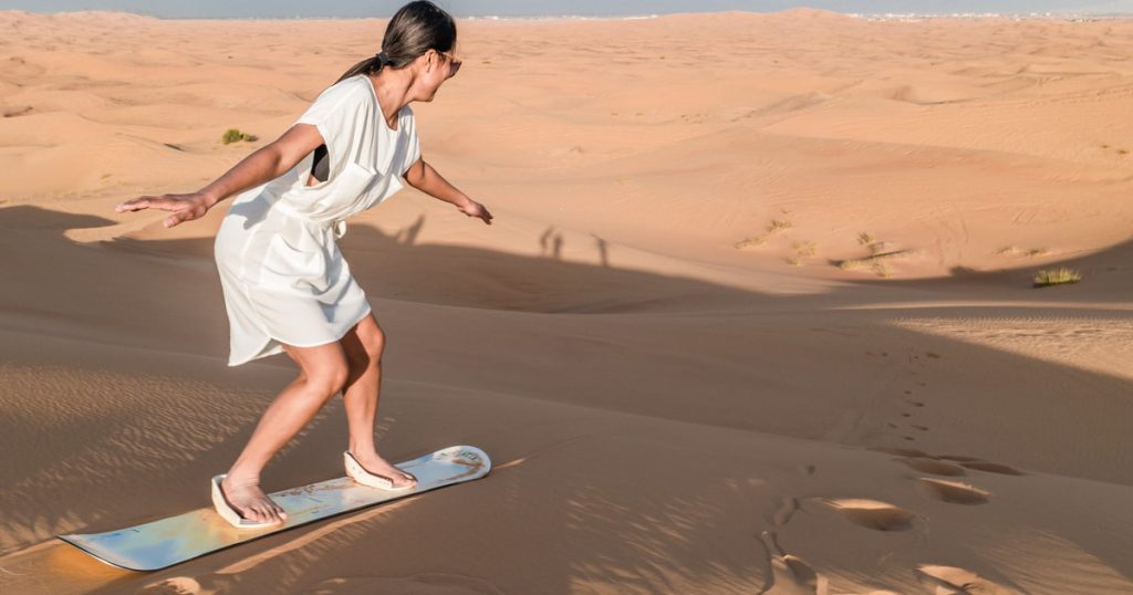 Sandboarding on the red dunes during a Dubai desert safari